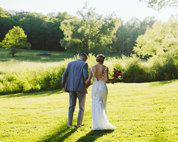 Rear view of bride and groom walking in the sunny countryside